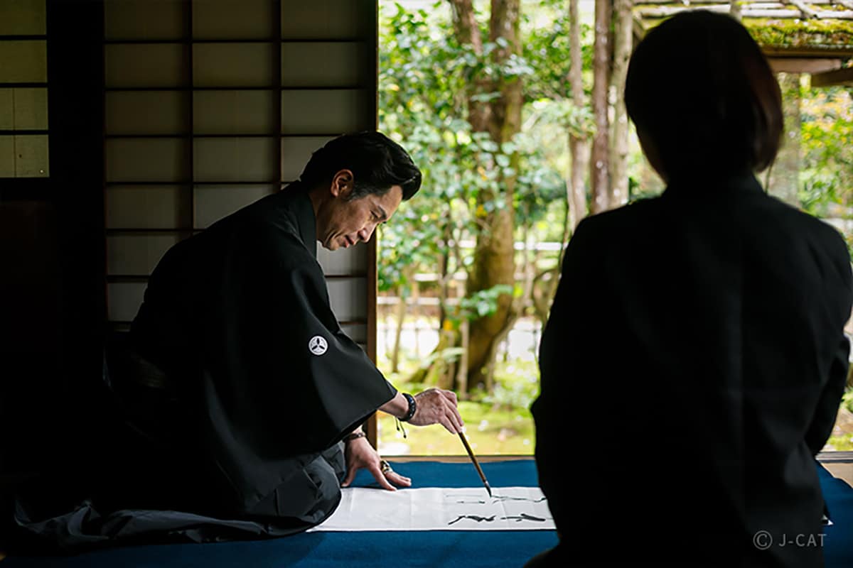 Luxury Experiences in Kyoto Man demonstrating calligraphy to a student